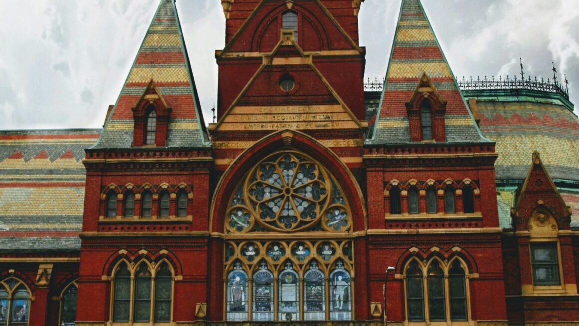 Memorial Hall in Harvard University showcasing Victorian Gothic architecture against a cloudy sky.