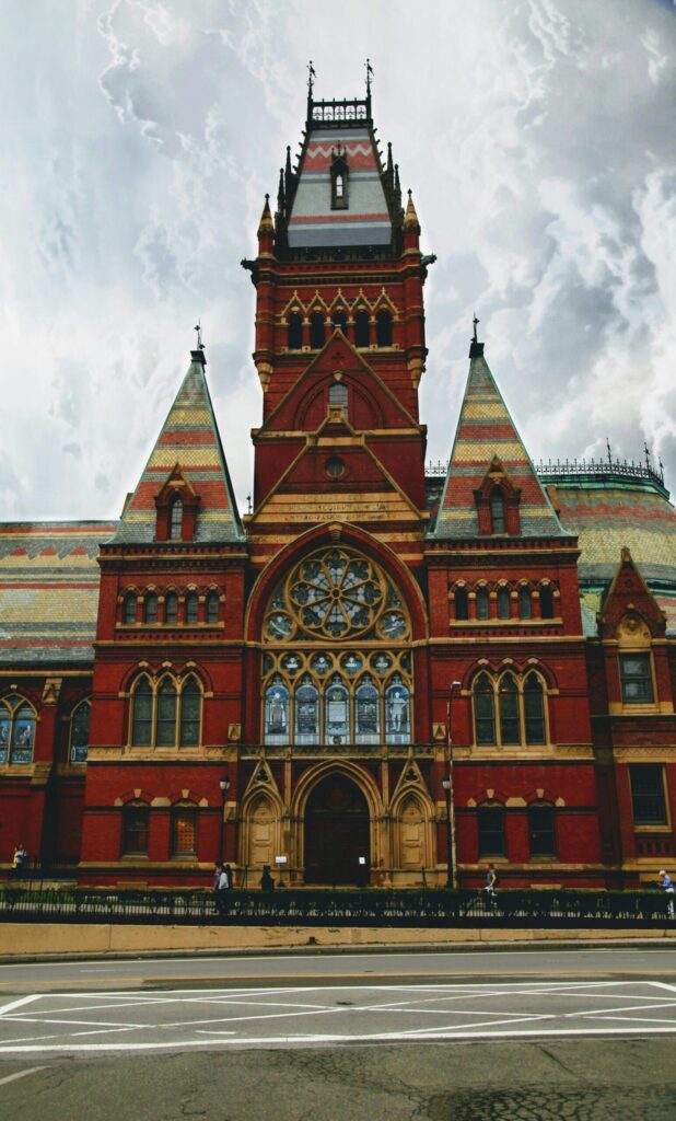Memorial Hall in Harvard University showcasing Victorian Gothic architecture against a cloudy sky.